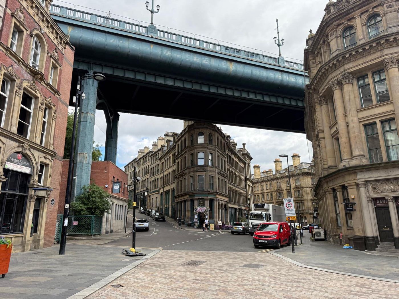 Cobbled street under the High Level Bridge in Newcastle, Victorian buildings either side.