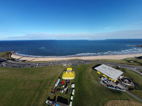 Big top on a clifftop green above a sandy bay