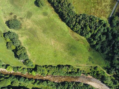 Drone view of a field running down to a river